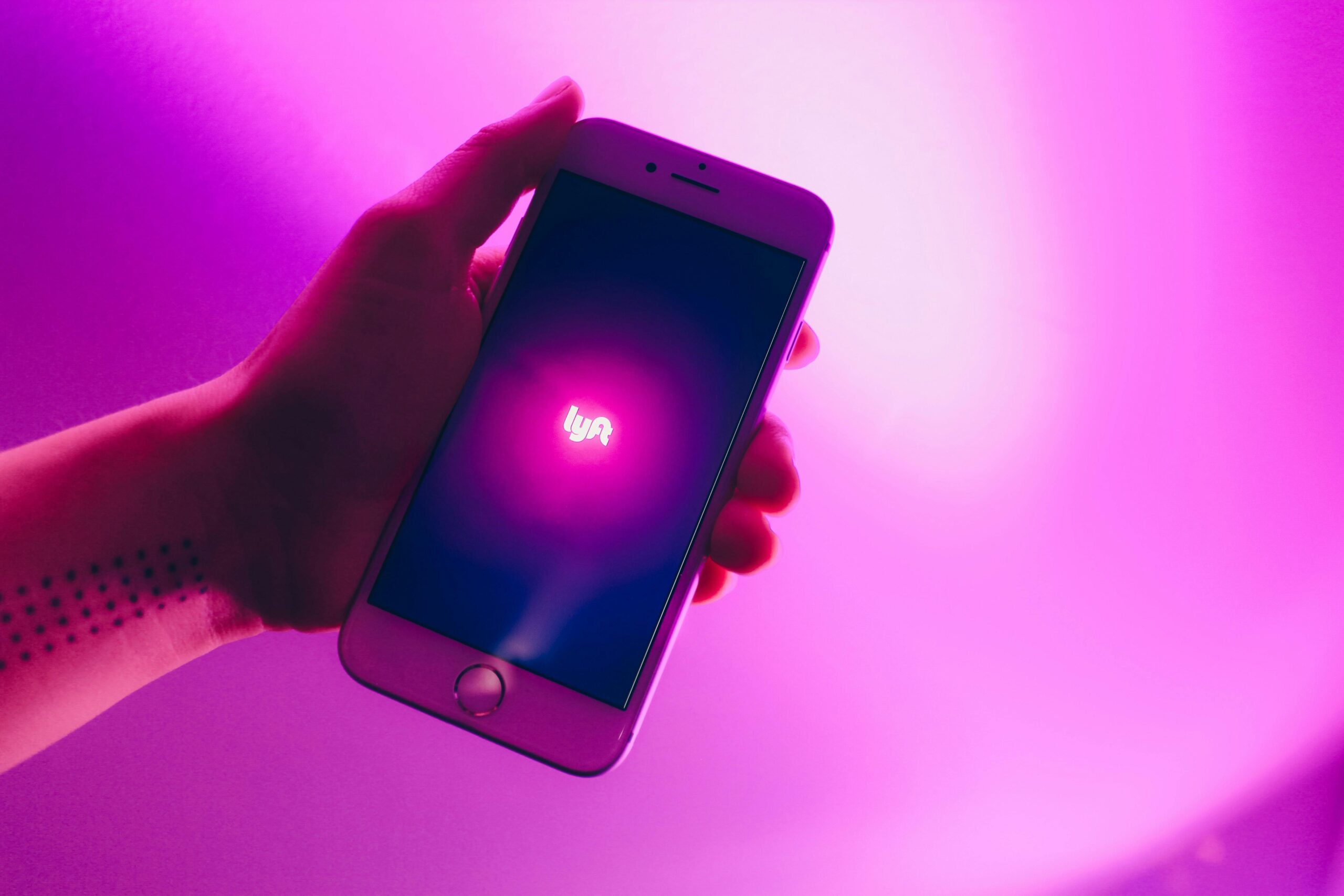 Lyft icon glowing on Iphone screen in a persons hand